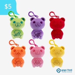 Six Yummy Gummy Backpack Buddies displayed side by side, each showing a different scented plush character with its unique color and design, all featuring clips for attaching to backpacks or bags.